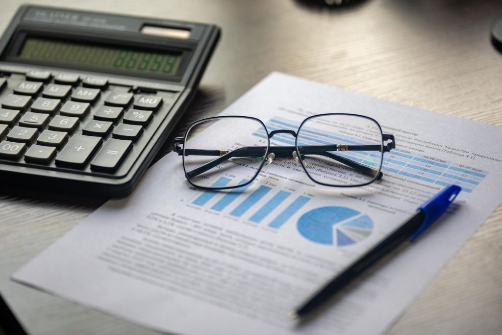 Calculadora, lentes y documento financiero sobre un escritorio, representando servicios de contabilidad